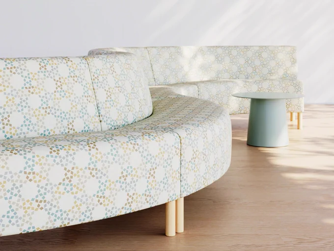 A curved modular sofa with a patterned Designtex fabric and teal accent table.