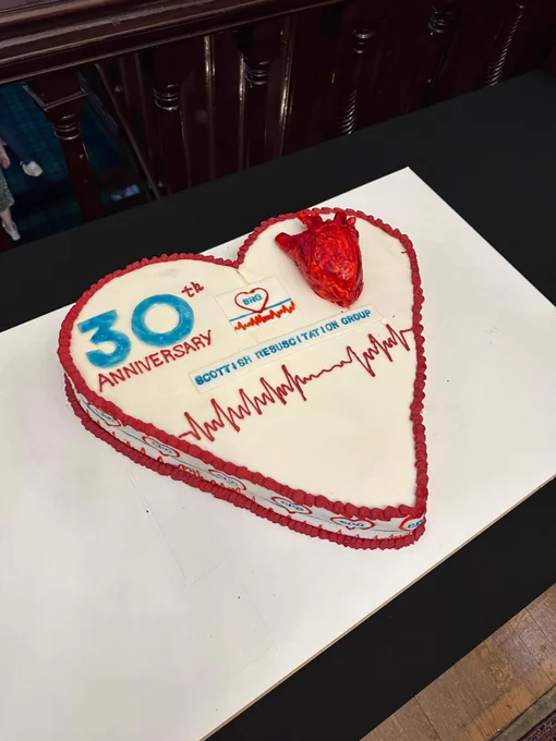 Heart-shaped cake that says 30th Anniversary Scottish Resuscitation Group with heart and ECG line decorations.