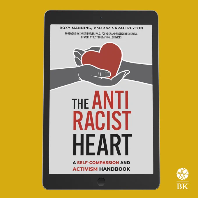 The cover of The Antiracist Heart is shown on an iPad, which stands against a yellow background.