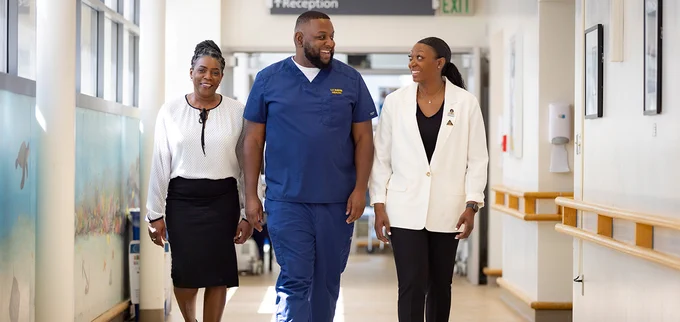 Calene Roseman, left, Aron King, middle, and and DaJanae Gresham-Ryder walking down a hospital hallway