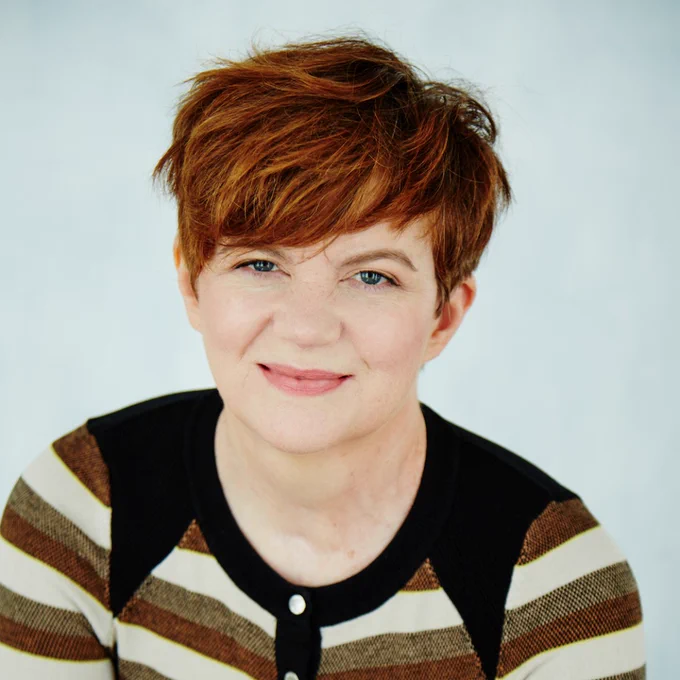Selected ArtScreen 2023 artist Sofya Gollan has short cropped red hair and is wearing a striped top.
