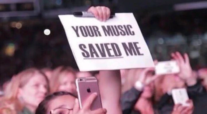 A sign being held up that says "your music saved me" 