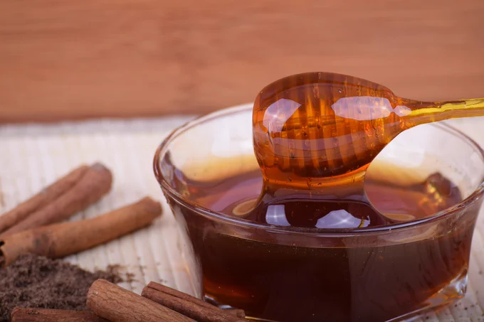 ciotola di miele con apposito cucchiaio di legno ricco di scanalature per spargerlo senza produrre gocce indesiderate