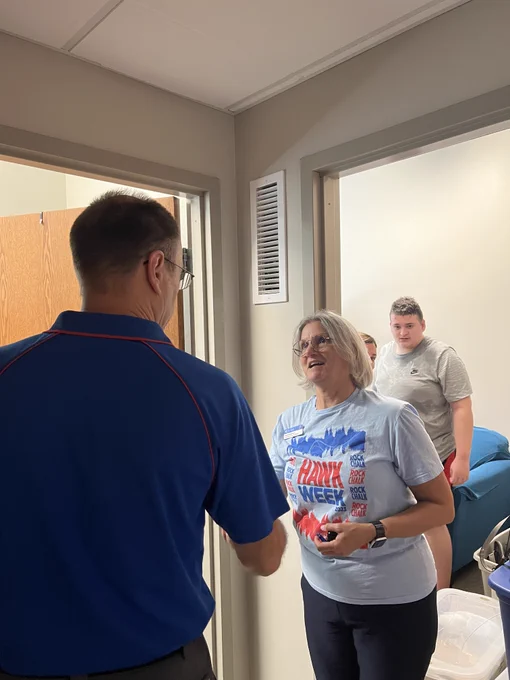 Provost and Executive vice chancellor Barbara A. Bichelmeyer talks with a father of a student moving into their room in a University of Kansas residence hall. An open door in the background shows a student standing in their new room along with bins of belongings.