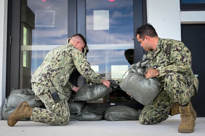 ABH2 Edwin Rodriguez, right, and ABH3 Robert Sutton stack sandbags in front of facility entrances at Naval Air Station Key West in preparation for Hurricane Idalia. 📸 Mass Communication Specialist 2nd Class Nicholas V. Huynh