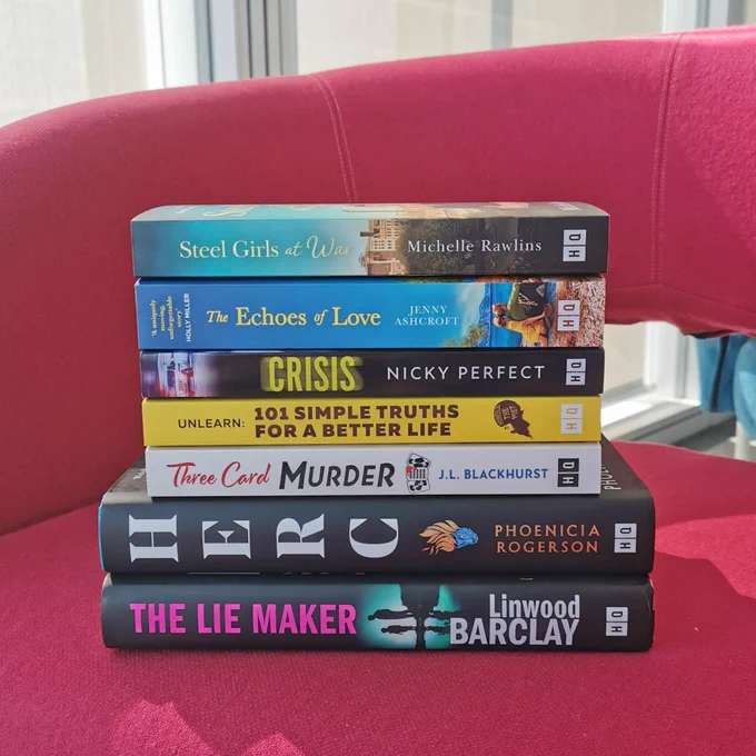 Photo of a stack of seven books on a pink chair.