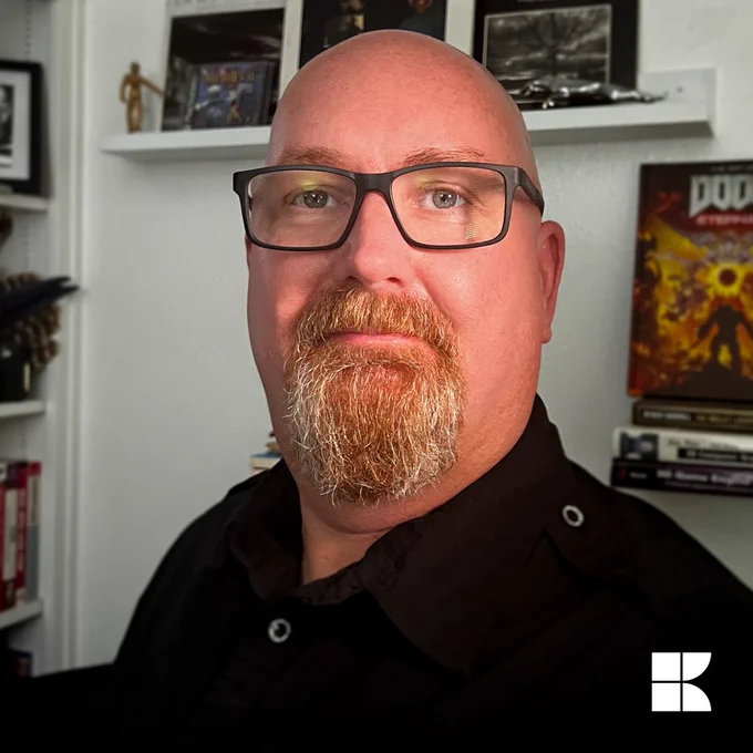Stephen standing in front of a book shelf, which also holds some merch from the game Doom.