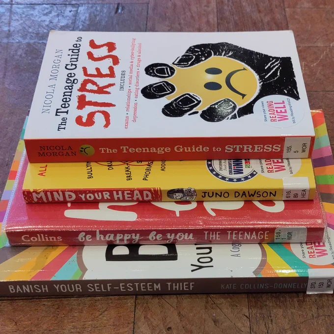 4 self-help books for Teens in a pile on parquet floor. From bottom: 'Banish Your Self-Esteem Thief'; 'Be Happy, Be You'; 'Mind Your Head'; 'The Teenage Guide To Stress'