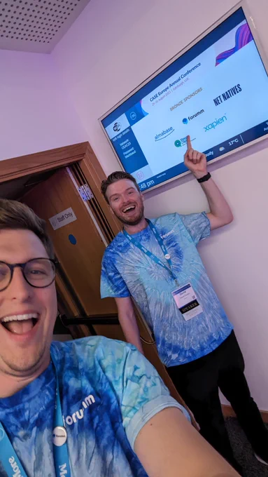 Tie dye shirts on two guys with one pointing at Forumm logo