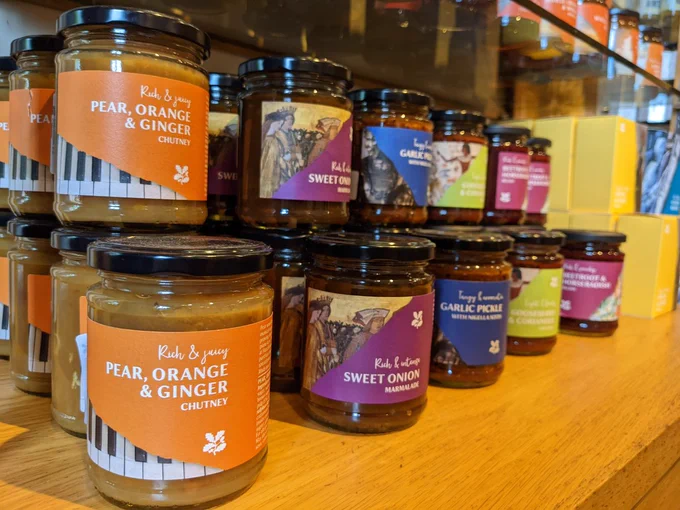 A row of jars of chutney with colourful labels. The visible labels are for jars of pear, orange and ginger chutney, sweet onion marmalade, and garlic pickle.