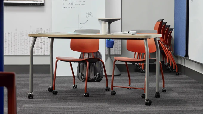 A classroom learning space with a Steelcase Learning Agree classroom table and two red Steelcase Learning tenor chairs.