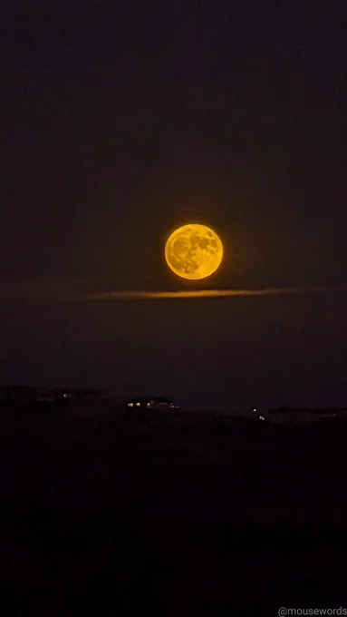 A full supermoon rising above a storm cloud