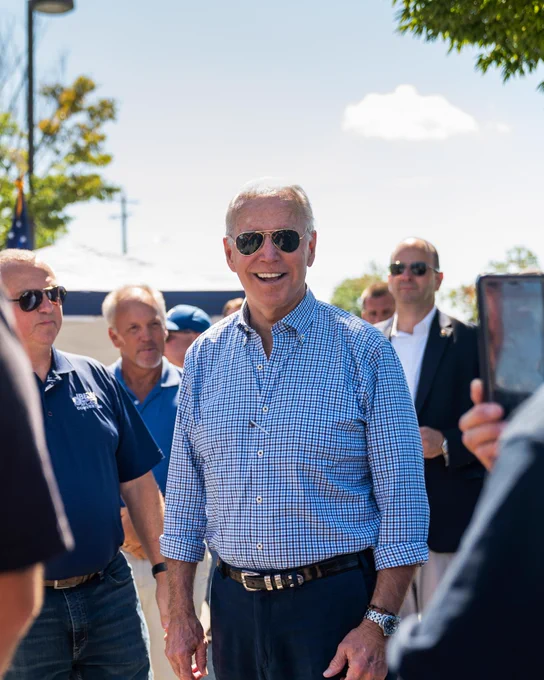 President Joe Biden wearing a button up and aviators. 