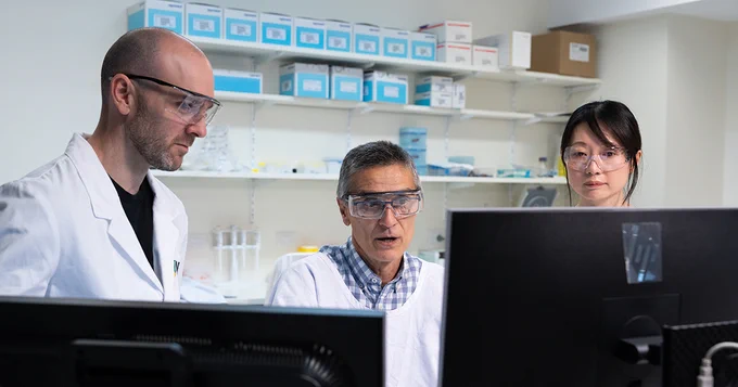 Three researchers are photographed looking at a computer monitor