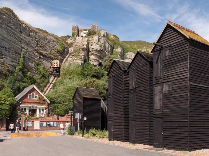 A photograph of four tall wooden sheds beside a cliff installed with a funicular railway.