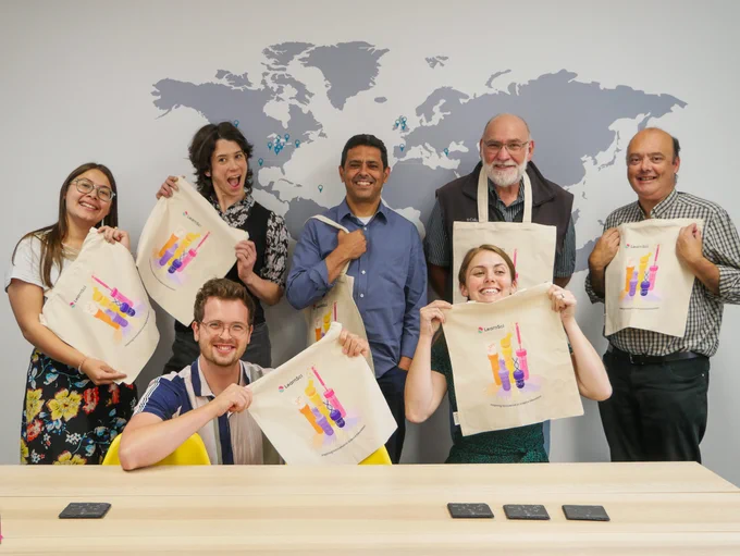 Image of some of the team posing with LearnSci tote bags. 