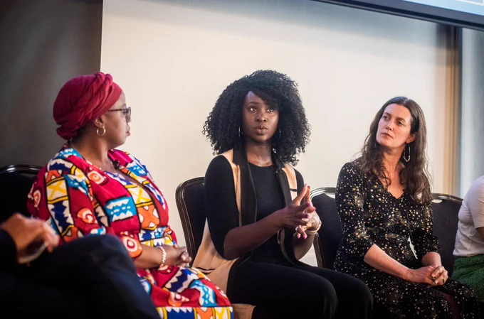 Three people are sitting side by side; the person in the middle is talking and the other two are looking at her.