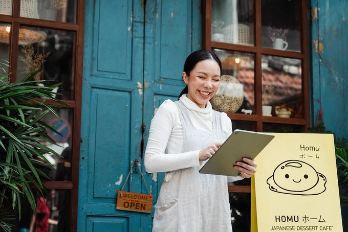 Cheerful woman with clipboard near cafe entrance
