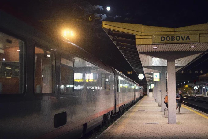 Nearly full moon on the platform of Dobova station. People are standing on the platform. to have a smoke. Laterns are enlightening the place.
