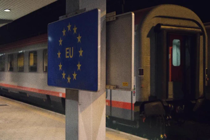 A big EU sign on the station's platform, behind the EC-train without an engine.