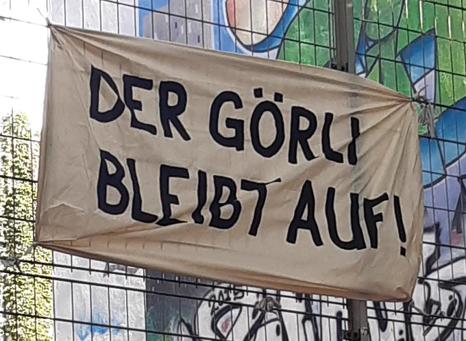 Transparent vor Grafitti-Hintergrund: "Der Görli bleibt auf!"