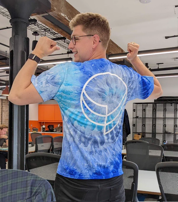Picture of Dan wearing a tie dye blue shirt with the Forumm speech bubble logo on the back. 