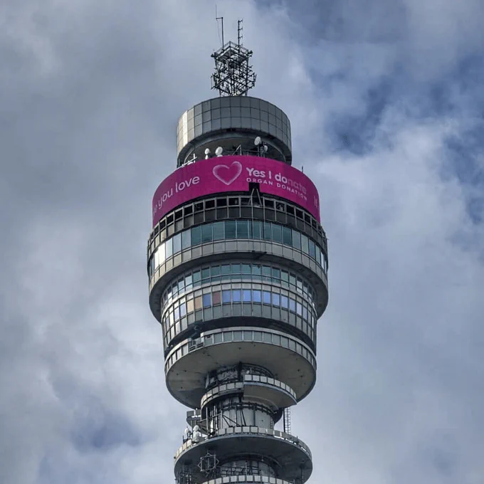 A photo of BT Tower with the pink Organ Donation logo displayed on the screen at the top of the tower.