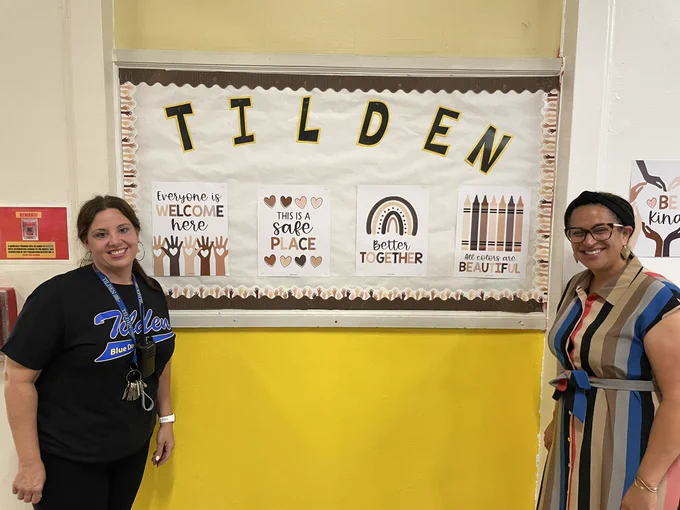 Picture with me and Principal Ramos on either side of a Tilden bulletin board
