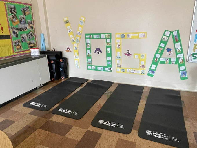 Four Yoga mats on the floor with yellow and green letters spelling yoga on the wall