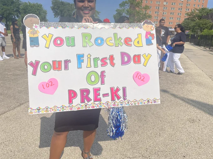 Robinson educator holding colorful sign: “You rocked your first day of pre-k”