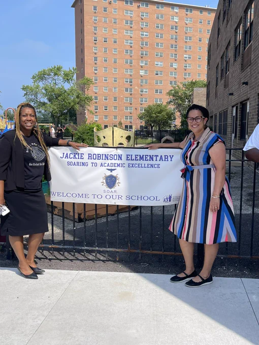 Me and Principal Ellis standing on either side of the Jackie Robinson ES banner