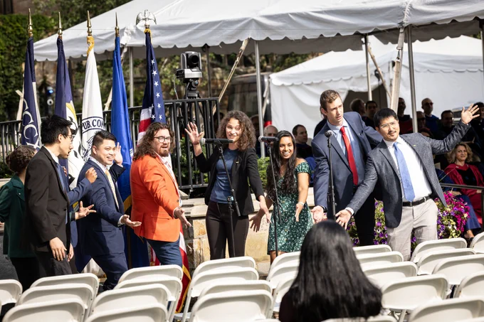 Photo of members of the a cappella group, The Yale Citations, at the 2023 Yale Graduate School of Arts and Sciences matriculation ceremony. Flags and white tent in background.