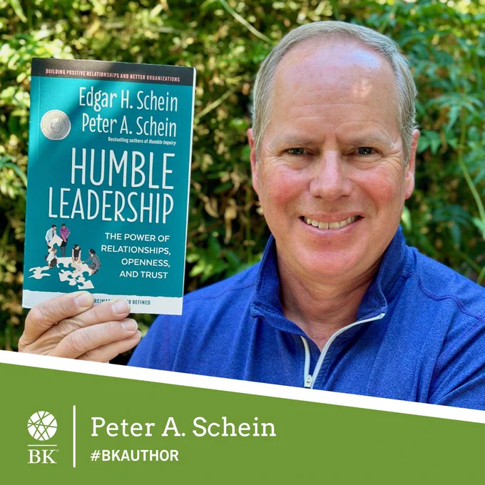 Author Peter A. Schein smiles and holds up a copy of his book, Humble Leadership, Second Edition.