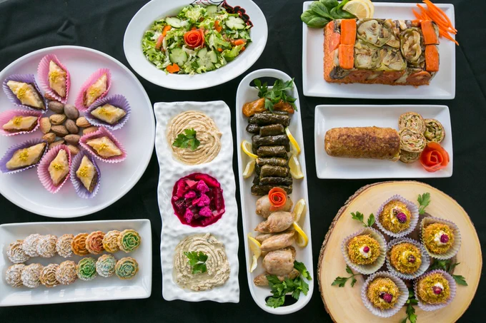 A colorful spread of Kurdish cuisine including dolmas, dips, salad and desserts.
