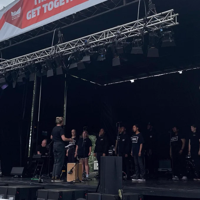 New YVC singing on stage. They're wearing black t-shirts which read 'New YVC'