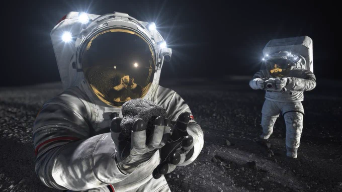 Illustration showing two astronauts in white moonwalking spacesuits on the Moon. The one in the foreground holds a large rock with an outstretched arm and shows it to the viewer. The rock is reflected in the helmet visor. In the back right is another astronaut taking photographs of the lunar surface. Their helmet lights are on. Credit: NASA