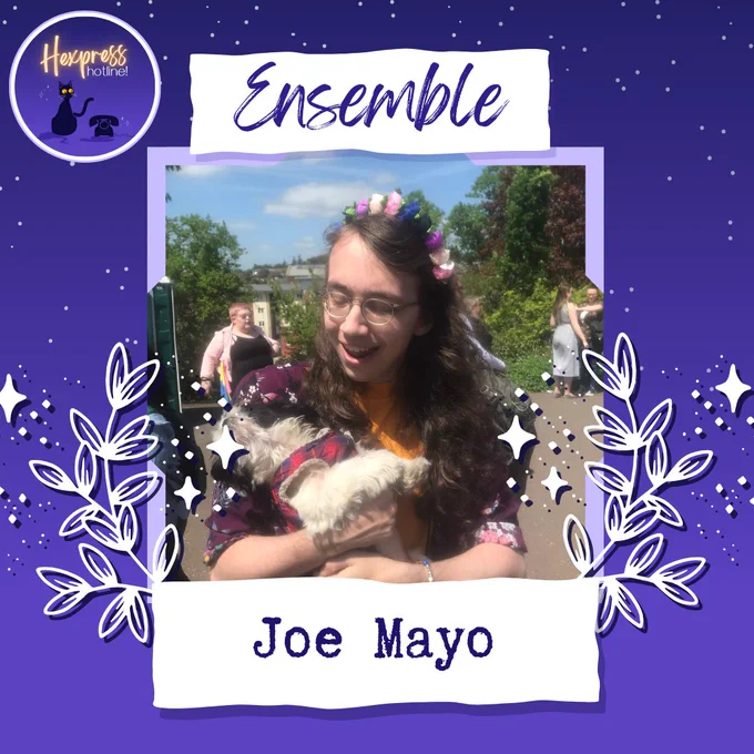 A photo on a purple background of a person with long brown hair and glasses, wearing a flower crown and holding a white dog with black ears and a tartan harness. In the top left corner is the Hexpress Hotline logo with a black cat and an old phone. Above the headshot is the label "Ensemble" in cursive writing.  Underneath the headshot are the words "Joe Mayo", and around the headshot are white leaves and stars.