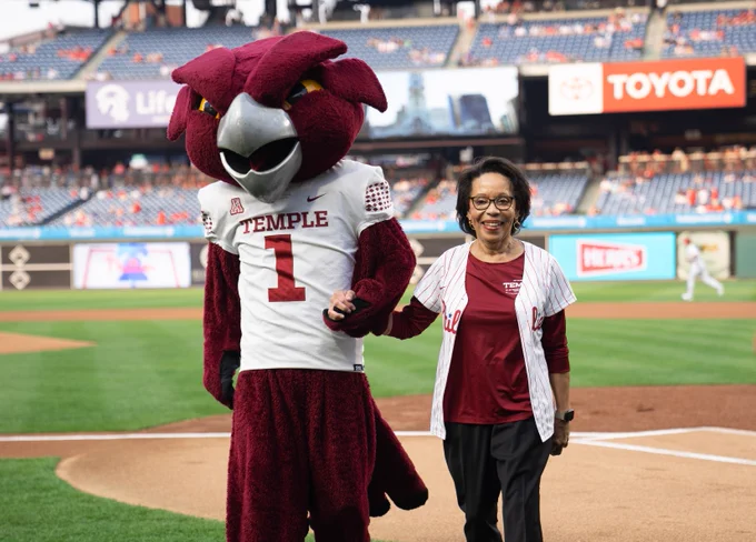JoAnne Epps walks off the field holding hands with Hooter the mascot