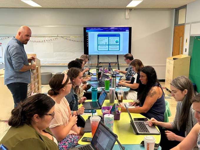 Teachers at a table using laptops