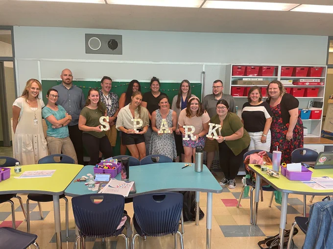 Teachers in a group photo holding letters that spell, "SPARK."