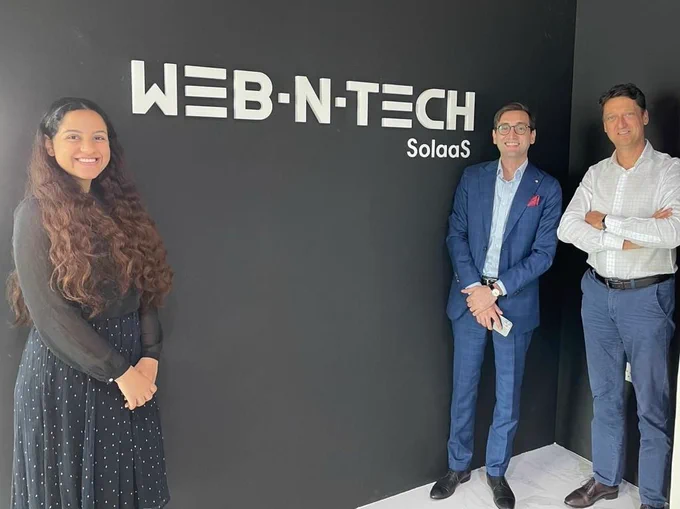 A woman  and two men stand on opposite sides of a dark wall bearing the company name WebNTech - Invest in Holland