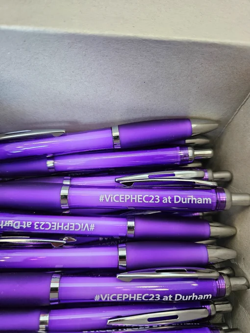 A box of purple ballpoint pens branded with the ViCEPHEC23 hashtag.