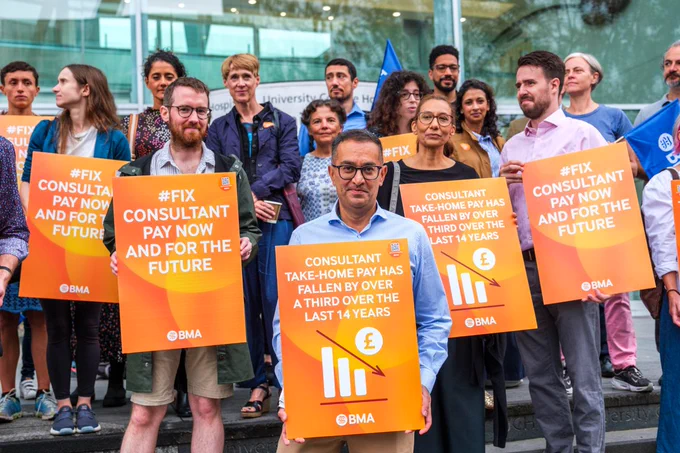 photo of consultants striking holding placards.