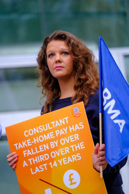 Women holding a BMA flag and holding an orange placard