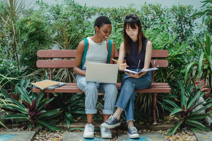 Content diverse female students studying in green park