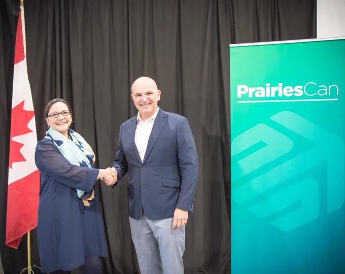Onlea's CEO, Adriana Lopez Forero, and MP Randy Boissonnault standing in front of the Canadian Flag and the PrairiesCan banner.