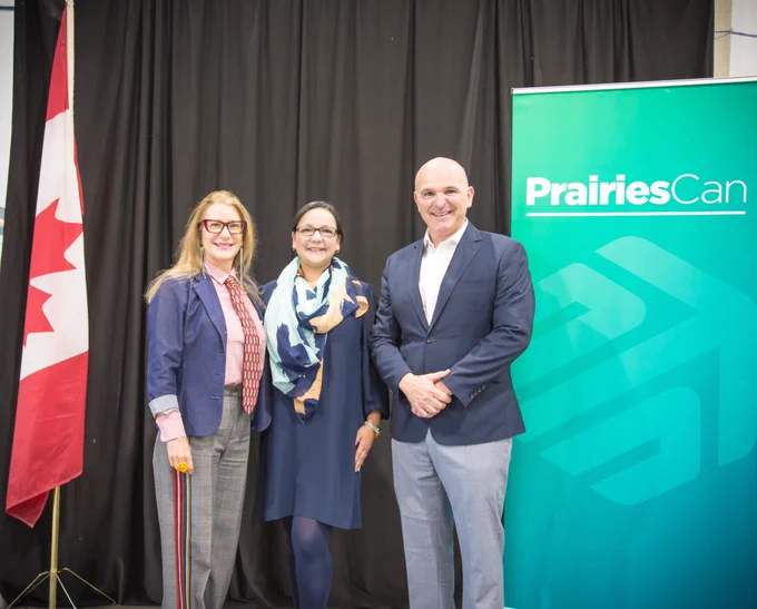 Onlea's CEO, Adriana Lopez Forero, MP Randy Boissonnault, and Catherine Warren from Edmonton Unlimited, standing in front of the Canadian Flag and the PrairiesCan banner.