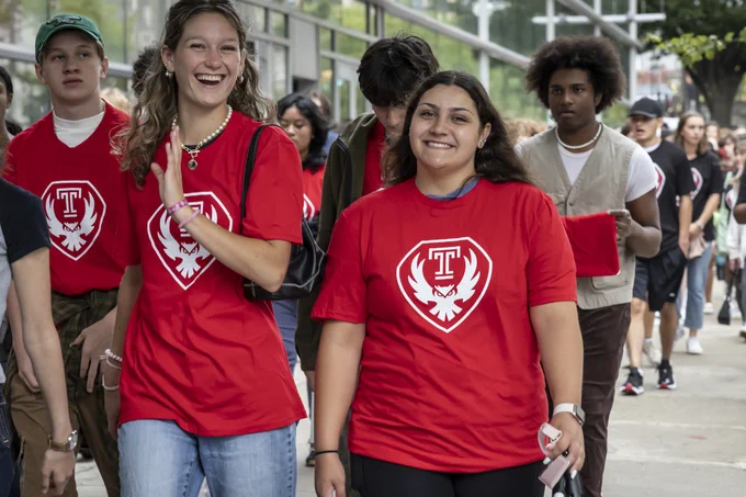 Students in new owl mark t-shirt walk down the street