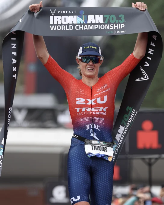 Taylor Knibb celebrates as she crosses the finish line holding the tape above her head at the 2023 IRONMAN 70.3 World Championship in Lahti, Finland.
