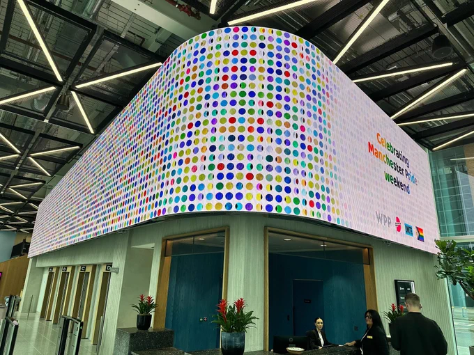 Colourful digital Screen at WPP Manchester Campus which says “Celebrating Manchester Pride Weekend”